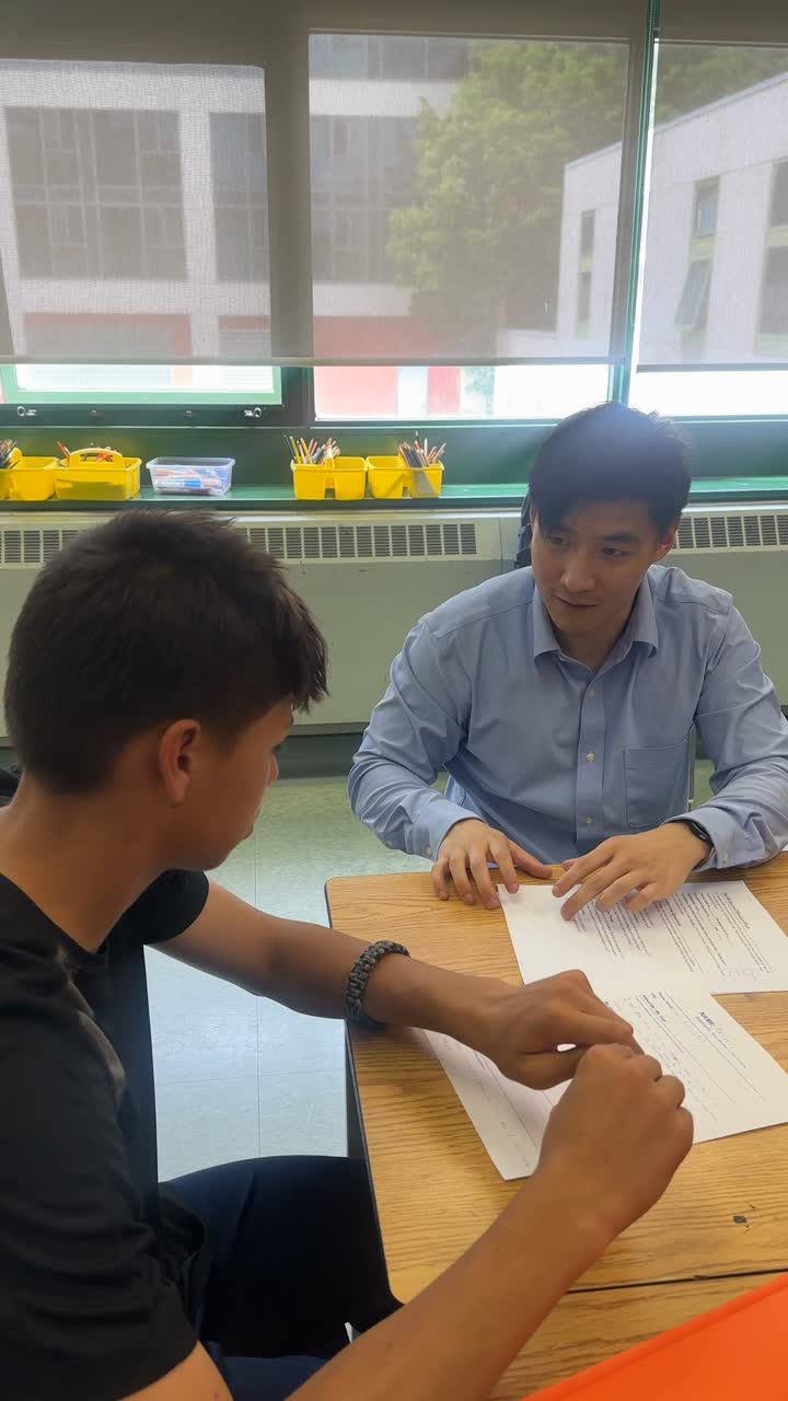 A volunteer and a young person reviewing a document together at a classroom table