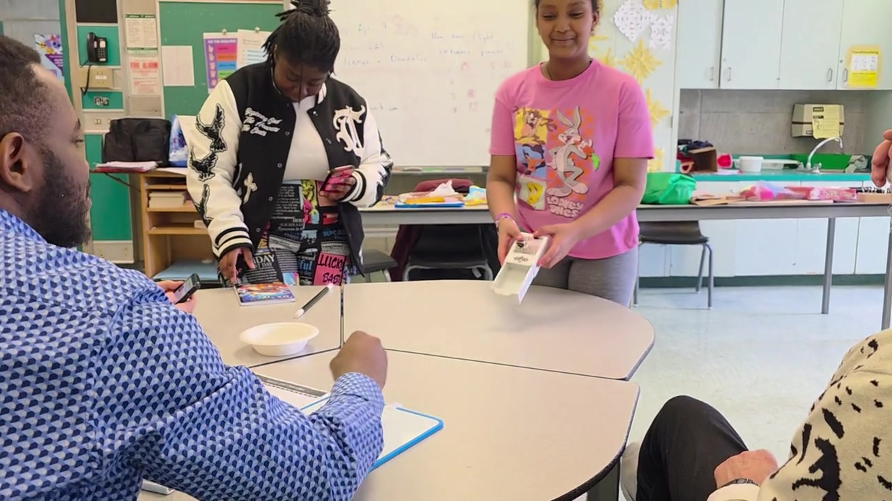 A young person demonstrating an activity to adult volunteers in a classroom