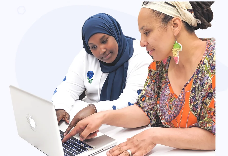 A youth tutor and an adult learner working together on a laptop