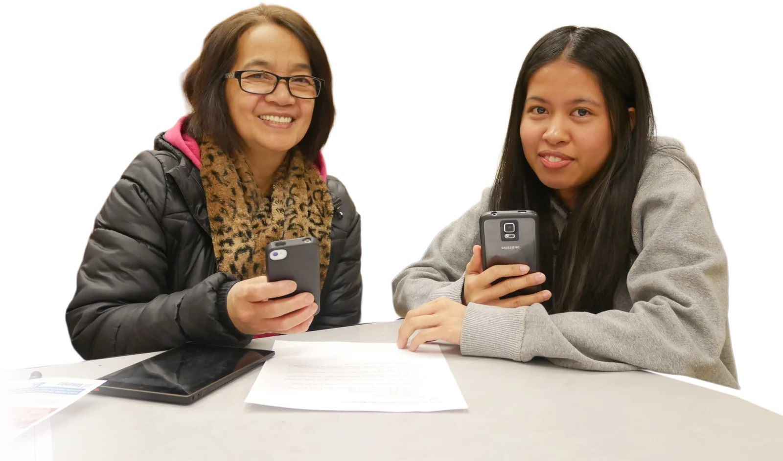 An adult learner and her youth tutor, smiling, each holding a phone